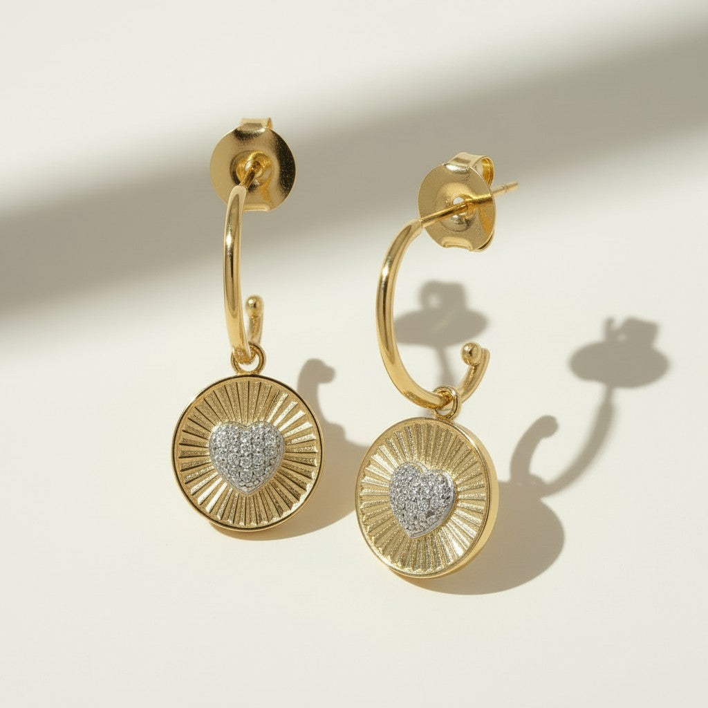 sunburst disc earrings flat lay, gold drop earrings detail, heart pavé earrings pair, huggie hoop drop earrings, textured gold earrings, statement drop earrings, sparkle disc earrings, gold heart earrings
