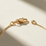 box chain bracelet flat lay, gold box link bracelet, delicate gold bracelet clasp, minimalist gold bracelet, 18k gold box chain, thin gold bracelet detail, dainty gold bracelet, gold bracelet clasp detail