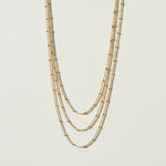 layered satellite necklace flat lay, three strand necklace clasp, cascading gold necklace construction, beaded chain necklace detail, 18k gold satellite chain, graduated necklace flat lay, multi strand necklace clasp detail, delicate layered gold necklace