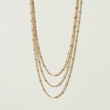 layered satellite necklace flat lay, three strand necklace clasp, cascading gold necklace construction, beaded chain necklace detail, 18k gold satellite chain, graduated necklace flat lay, multi strand necklace clasp detail, delicate layered gold necklace