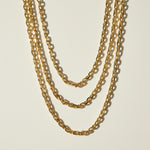  chunky gold chain necklace, oval link chain necklace, layered gold chains on model, gold cable chain necklace, statement chain necklace, graduated length chain layering, bold link necklace