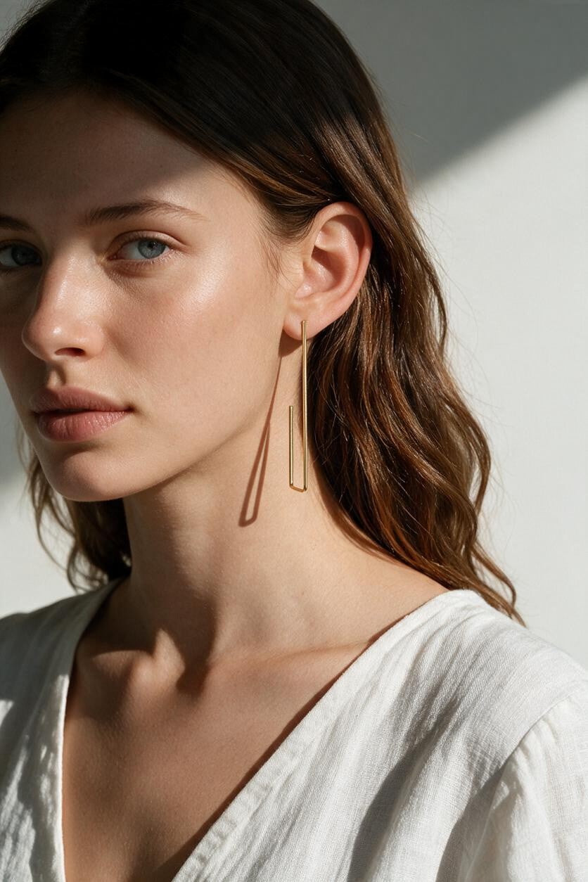 long gold rectangle earrings on model, geometric wire earrings, minimalist gold drop earrings, elongated open hoop earrings, modern gold earrings, lightweight statement earrings, architectural earrings, thin gold wire earrings, contemporary gold jewelry, linear gold earrings, women’s geometric earrings, elegant everyday earrings
