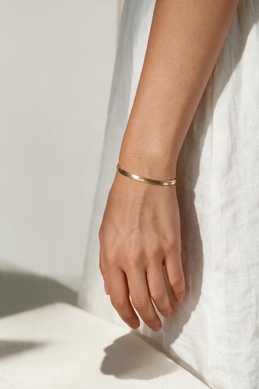 gold herringbone bracelet on wrist, flat gold chain bracelet, slim snake chain bracelet, dainty gold bracelet, minimalist gold bracelet, adjustable gold bracelet, everyday gold bracelet, layering bracelet, shiny gold chain bracelet, women’s gold bracelet, flat herringbone bracelet, sleek wrist jewelry