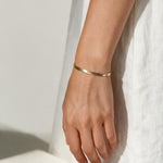 gold herringbone bracelet on wrist, flat gold chain bracelet, slim snake chain bracelet, dainty gold bracelet, minimalist gold bracelet, adjustable gold bracelet, everyday gold bracelet, layering bracelet, shiny gold chain bracelet, women’s gold bracelet, flat herringbone bracelet, sleek wrist jewelry