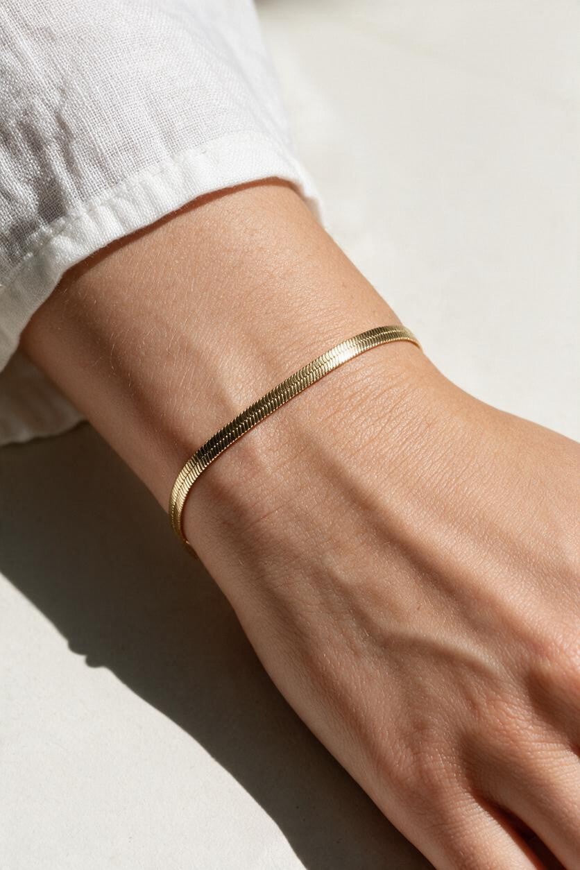 gold herringbone bracelet on wrist, flat gold chain bracelet, slim snake chain bracelet, dainty gold bracelet, minimalist gold bracelet, adjustable gold bracelet, everyday gold bracelet, layering bracelet, shiny gold chain bracelet, women’s gold bracelet, flat herringbone bracelet, sleek wrist jewelry