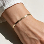 gold herringbone bracelet on wrist, flat gold chain bracelet, slim snake chain bracelet, dainty gold bracelet, minimalist gold bracelet, adjustable gold bracelet, everyday gold bracelet, layering bracelet, shiny gold chain bracelet, women’s gold bracelet, flat herringbone bracelet, sleek wrist jewelry