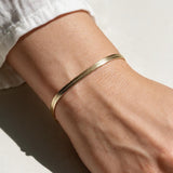 gold herringbone bracelet on wrist, flat gold chain bracelet, slim snake chain bracelet, dainty gold bracelet, minimalist gold bracelet, adjustable gold bracelet, everyday gold bracelet, layering bracelet, shiny gold chain bracelet, women’s gold bracelet, flat herringbone bracelet, sleek wrist jewelry