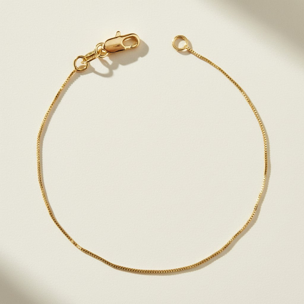 box chain bracelet flat lay, gold box link bracelet, delicate gold bracelet clasp, minimalist gold bracelet, 18k gold box chain, thin gold bracelet detail, dainty gold bracelet, gold bracelet clasp detail