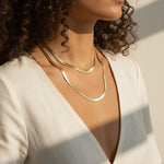 layered herringbone necklaces, double herringbone chain, gold chain layering on model, 18k gold overlay necklace set, herringbone necklace editorial, layered gold necklaces sunset, mixed length herringbone chains, gold chain styling inspiration