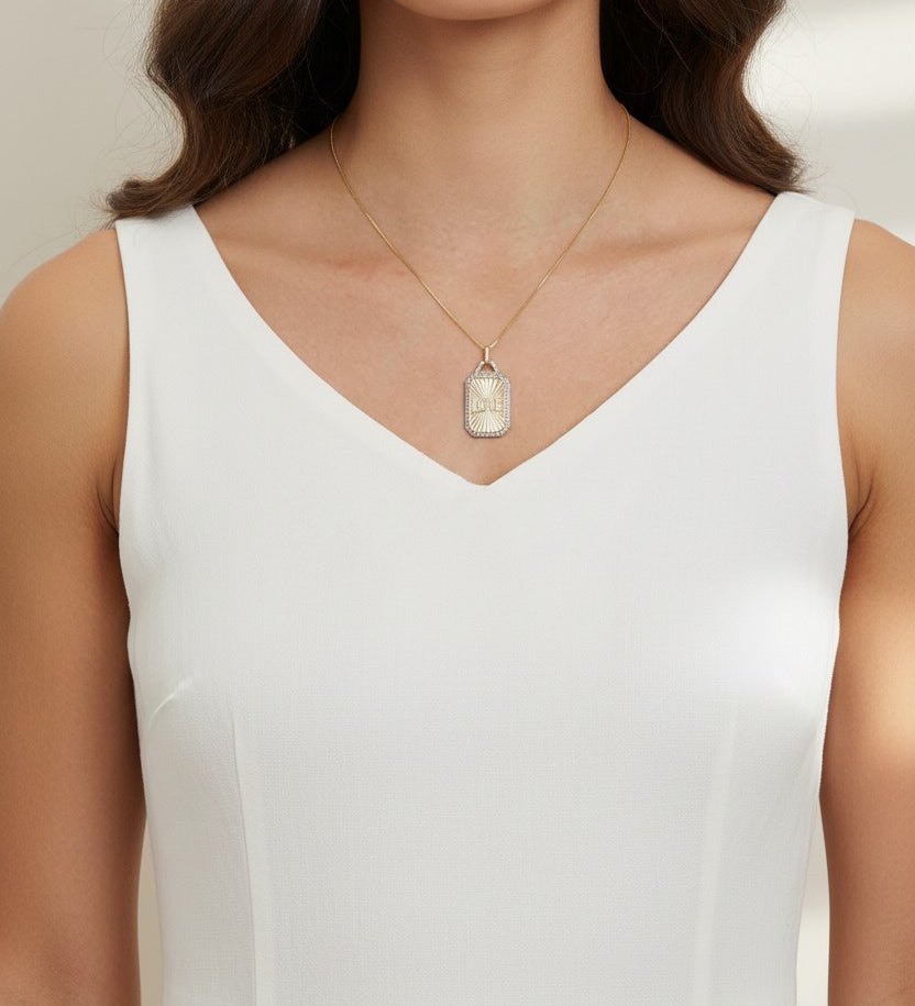 love pendant necklace on model, gold tag necklace lifestyle, sunburst pendant necklace worn, pavé love necklace styled, engraved love pendant on neck, long chain pendant necklace, statement gold necklace, script love necklace outfit