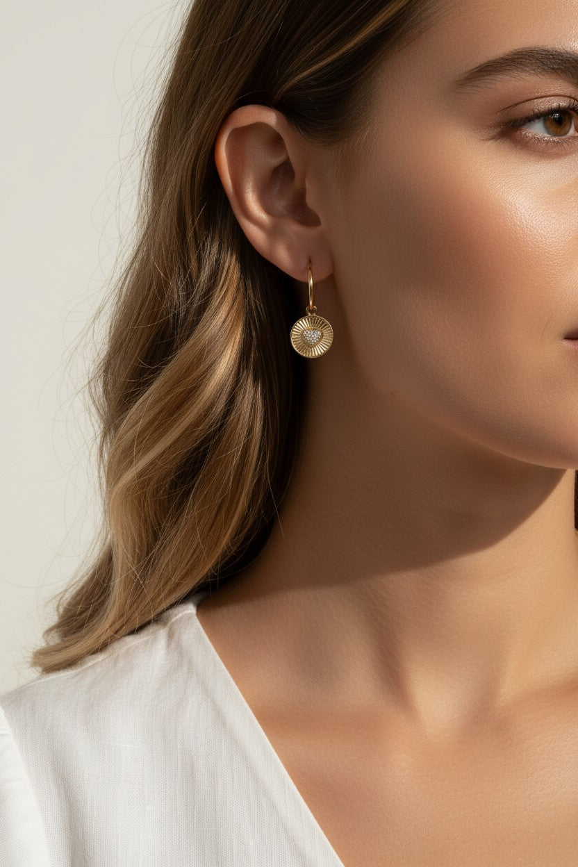 sunburst disc earrings, gold drop earrings on model, heart pavé earrings, huggie hoop drop earrings, textured gold earrings, statement drop earrings, sparkle disc earrings, everyday gold earrings