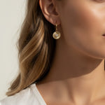 sunburst disc earrings, gold drop earrings on model, heart pavé earrings, huggie hoop drop earrings, textured gold earrings, statement drop earrings, sparkle disc earrings, everyday gold earrings