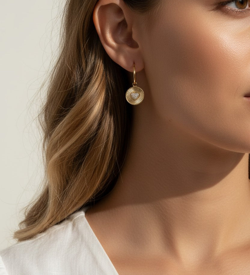 sunburst disc earrings, gold drop earrings on model, heart pavé earrings, huggie hoop drop earrings, textured gold earrings, statement drop earrings, sparkle disc earrings, everyday gold earrings