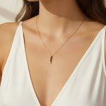 black pave dagger necklace worn, gold necklace with black crystals styled, minimalist pendant necklace fit, edgy gold necklace lifestyle photo, dainty necklace close-up, black crystal pendant on model