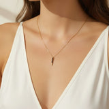 black pave dagger necklace worn, gold necklace with black crystals styled, minimalist pendant necklace fit, edgy gold necklace lifestyle photo, dainty necklace close-up, black crystal pendant on model