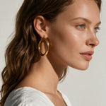 classic gold hoop earrings on model, gold tube hoop earrings, polished gold hoops, medium gold hoop earrings, thick gold hoops, everyday gold hoops, timeless hoop earrings, minimalist gold hoops, lightweight chunky hoops, hoop earrings for long hair, gift for her, summer linen style jewelry