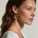 classic gold hoop earrings on model, gold tube hoop earrings, polished gold hoops, medium gold hoop earrings, thick gold hoops, everyday gold hoops, timeless hoop earrings, minimalist gold hoops, lightweight chunky hoops, hoop earrings for long hair, gift for her, summer linen style jewelry